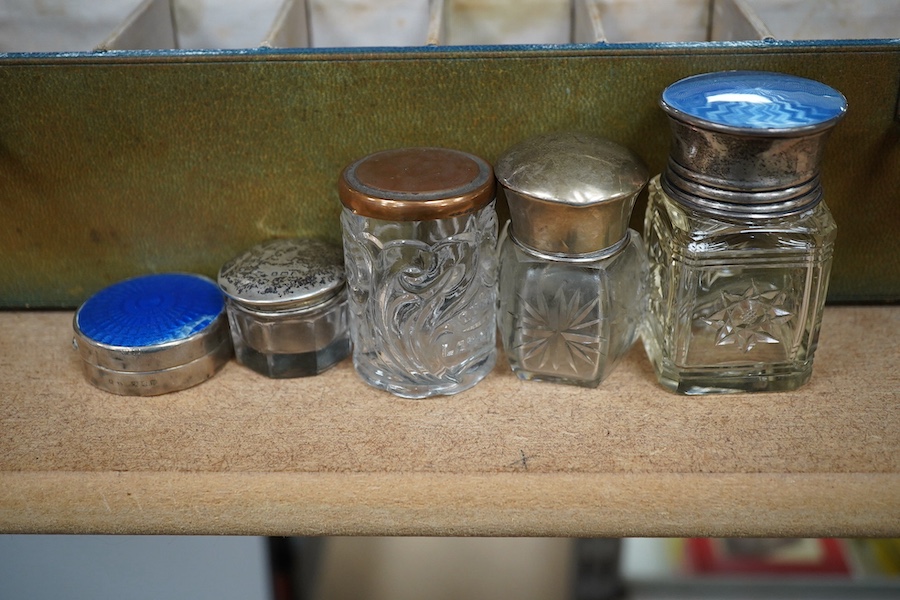 A green leather sectioned box containing a collection of cut glass, silver mounted and silver plated boxes and jars, some with guilloche enamel lids, largest 7cm high